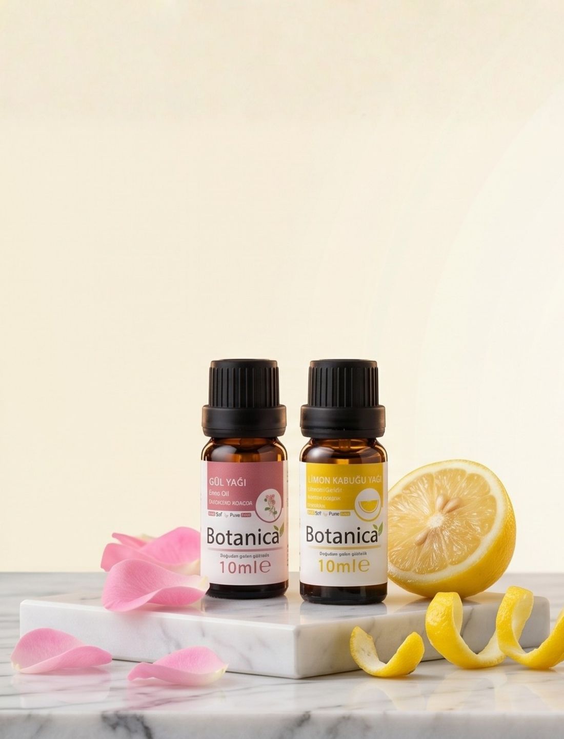 Mermer üzerinde Botanica gül ve limon kabuğu yağları, yanında limon dilimleri ve gül yaprakları